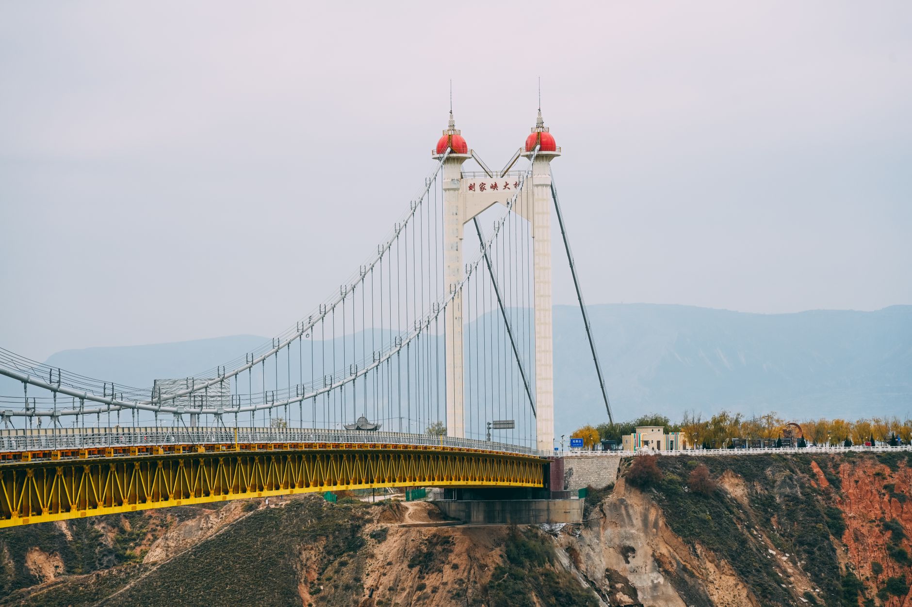 Pont suspendu moderne au-dessus d’un canyon escarpé sous un ciel couvert.